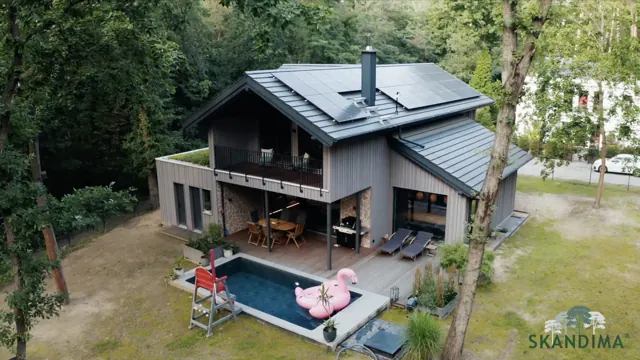 Luftaufnahme eines Holzhauses mit Pool und Flamingo-Schwimmtier am Waldrand