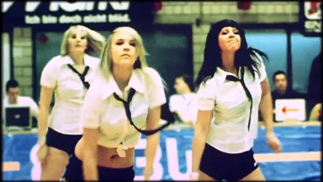 Drei Cheerleaderinnen tanzen in einer Sporthalle, Bild auf 16-mm-Film