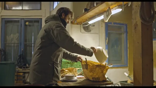 Ein junger Mann packt in einer Scheune Gemüse in Papiertüten