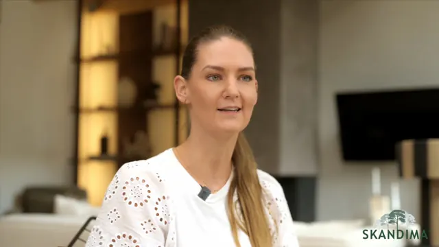 Eine Frau erzählt in einem Interview in ihrem Wohnzimmer
