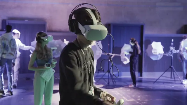 Jugendliche mit VR-Brillen in einem violett beleuchteten Raum